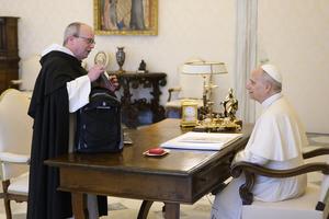 Dominican Father Thomas Joseph White reaches into his backpack April 1 to offer Pope Leo XIV some bluegrass music made entirely by Dominican friars.