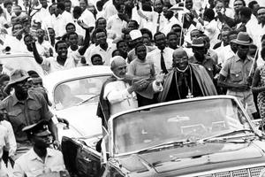 Pope Paul VI, standing in an open car, waves to the welcoming crowd jamming the road to Kampala on July 31, 1969. At the Pope's right is Archbishop E.K. Nsubuga of Kampala.