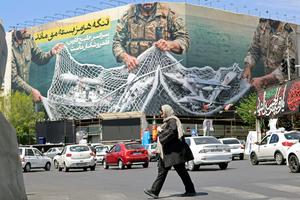 A woman walks past a giant billboard reading ‘The Strait of Hormuz remains closed’ at Revolution Square in Tehran on April 12.