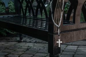 A rosary hangs on a bench.
