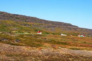 A Catholic chapel stands on a mountainside in Vatnsfjörður (Vatnsfjarðarkirkja), in Iceland’s Westfjords, under a clear summer sky.
