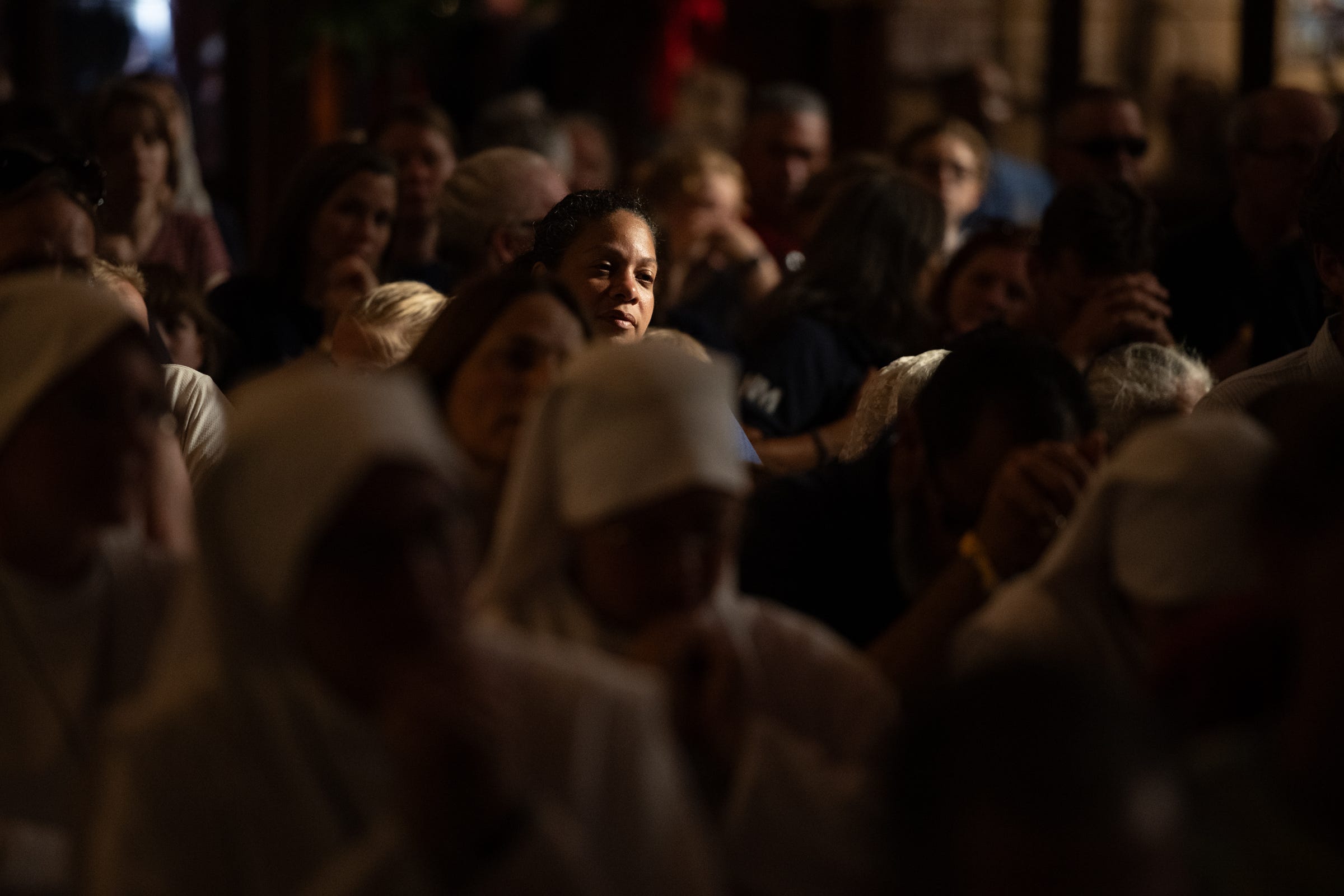 In the dim light of the cathedral, one face catches the glow…a quiet reminder that every procession, however grand, finally arrives at the human heart.