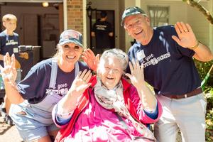 JT Olson (right) smiles alongside a widow and volunteers during a Both Hands service project. 