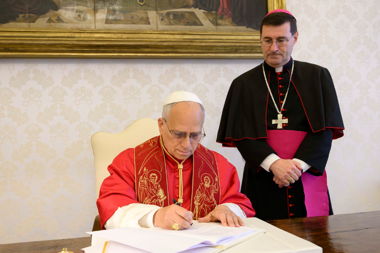 Pope Leo XIV signs his first encyclical, "Magnifica Humanitas," on May 15, 2026, in the apostolic palace at the Vatican, in the presence of Archbishop Paolo Rudelli, substitute for general affairs of the Secretariat of State. 