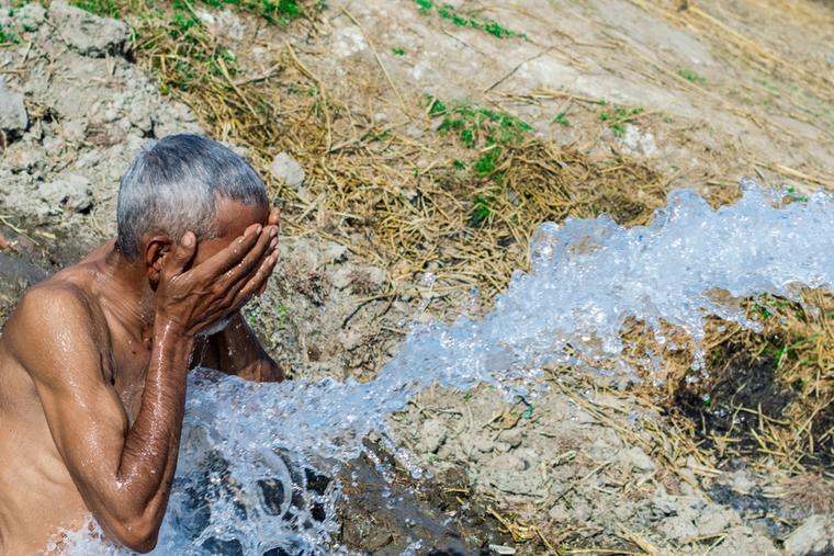 An elderly man washes his face at a tube well to find relief from extreme heat in Pakistan. 