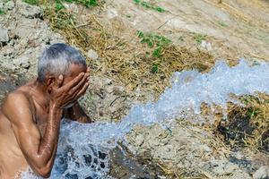 An elderly man washes his face at a tube well to find relief from extreme heat in Pakistan. 