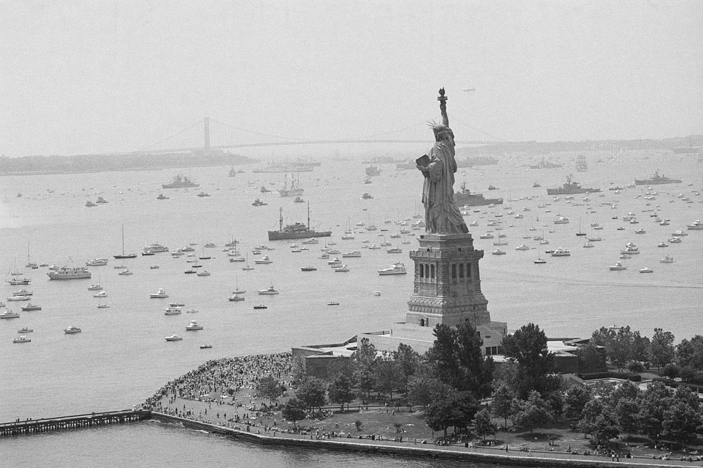 Long Line Of Ships Sails Past Statue getty