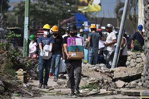 Volunteers carry boxes of humanitarian aid amid debris following earthquakes in Caraballeda, La Guaira state, Venezuela, on June 26, 2026. 