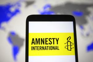 In this photo illustration, an Amnesty International logo is seen on a smartphone screen. 