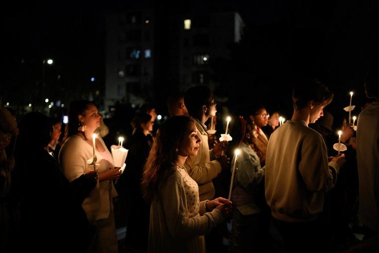 Christians enter a church, holding candles, to attend the Easter Vigil Mass on April 4, 2026, in Lyon.